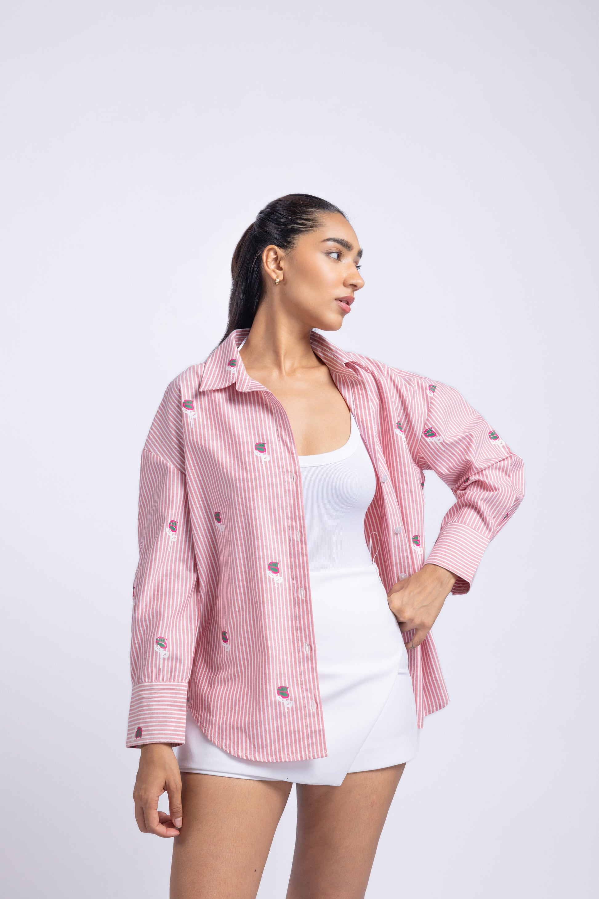 Woman wearing a pink checkered shirt over a white top and shorts on a light purple background