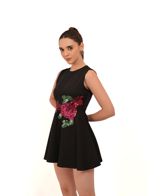 Woman wearing a black dress with floral embellishments on a white background